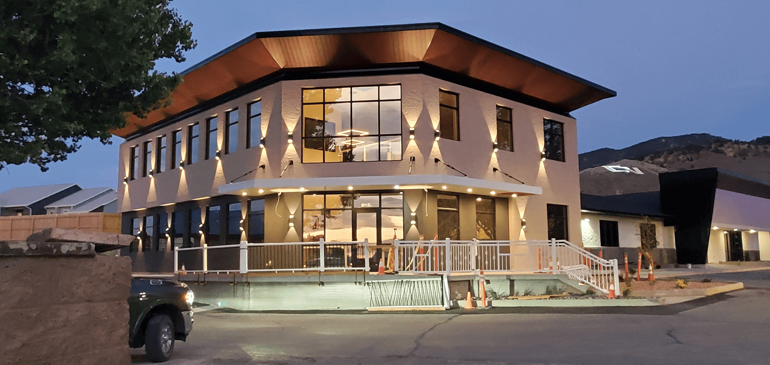 Modern two-story building with large glass windows at dusk.